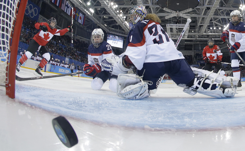 Goalkeeper Jesse Vetter and Kendall Coyne of the United States look back at the puck in the net as Meghan Agosta, left, of Canada celebrates her goal Wednesday at Sochi, Russia. Vetter later gave up a controversial goal as Canada won, 3-2.