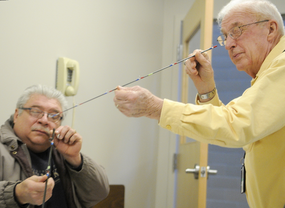 FLYING HIGH: Volunteer Don Taylor, right, inspects a section of a fly rod that veteran Dwaine LaChance assembled Wednesday at VA Maine Healthcare Systems-Togus during a meeting of Project Healing Waters. The group helps active and former service members experience fly fishing.