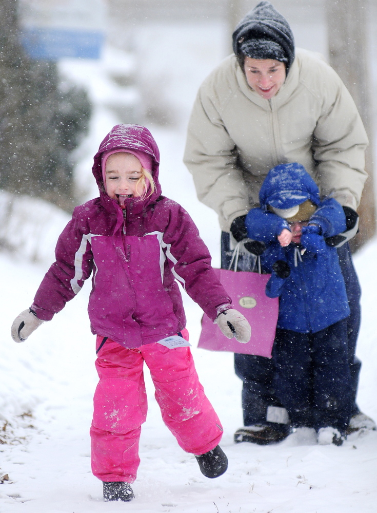 SNOW DAZE: Emerson Hardy, 4, samples a snow flake Thursday while walking home with her brother, Oscar, 2, and mother, Shelby. The trio had walked and shopped near their Hallowell home as the snowstorm arrived.