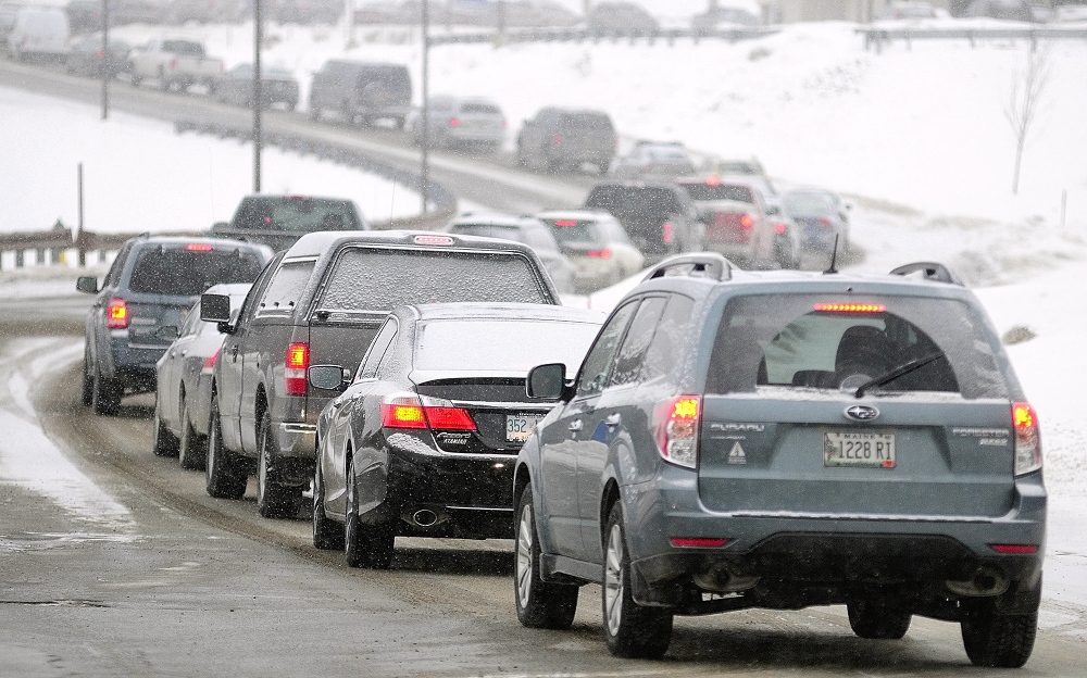 SLOW GOING: A long line of cars heads down Commerce Drive toward Route 27 Thursday. There are several state government offices in the Central Maine Commerce Center and state workers in Kennebec and three other counties were let out of work early because of the snow storm.