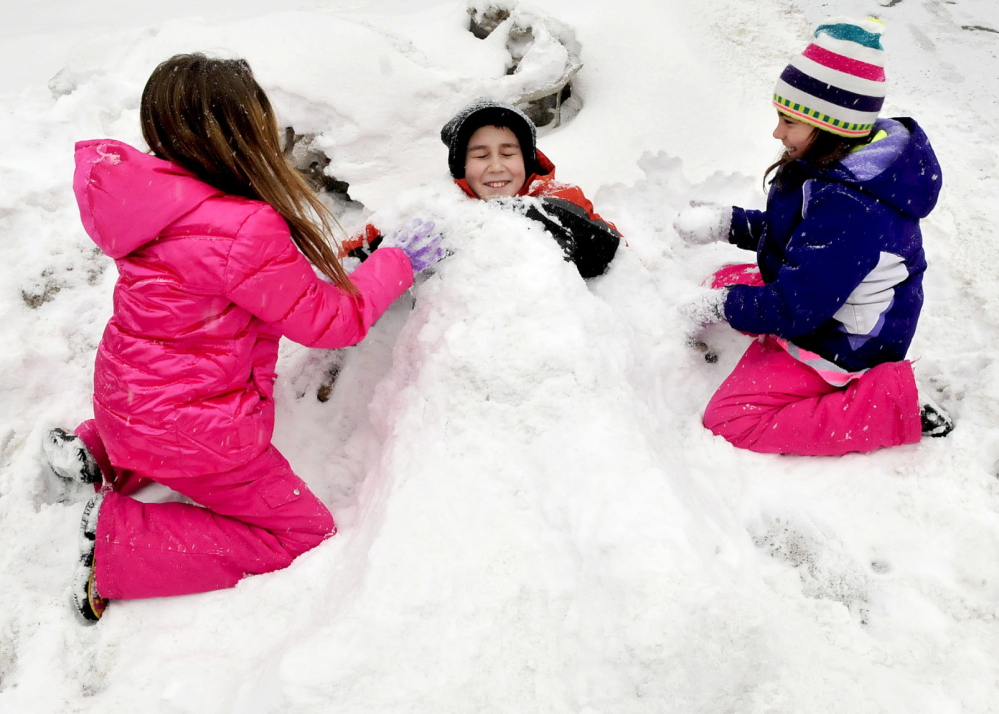 HAPPY DAYS: These kids got an early dismissal day on Thursday, because of the snowstorm and time to play outdoors. Burying Nicholas Bradley up to his neck in snow is Hannah Kellam, left, and Danielle Bradley.