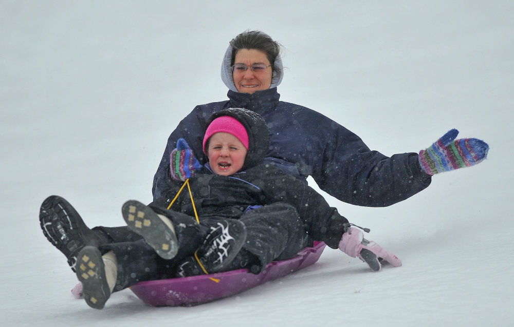 SLED HEADS: Karen Chase and Ysa Boothman, 7, cruise down the hill at Quarry Road Recreational Area in Waterville on Thursday as snow begins to fall.