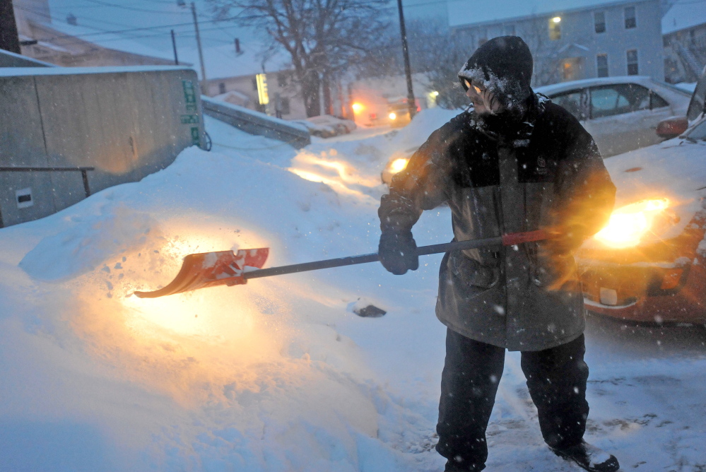 Staff photo by Michael G. Seamans STAYING AHEAD: Thomas Beeney clears the walkways at the Waterville Public Library as snow falls on Thursday. The winter storm is expecting to deposit at least one foot of fresh powder before moving out this afternoon.
