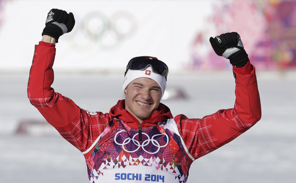 Switzerland’s Dario Cologna celebrates winning the gold during the flower ceremony for the men’s 15K classical-style cross-country race at the 2014 Winter Olympics Friday.