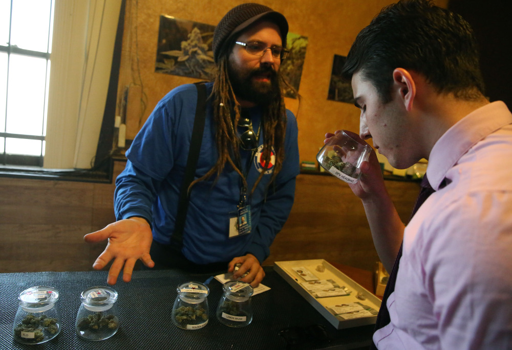 Customer Paxton Berlanga, of Indiana, right, smells a strain of marijuana, while being helped by employee Billy Archilla, inside the retail marijuana shop at 3D Cannabis Center, in Denver, Friday.