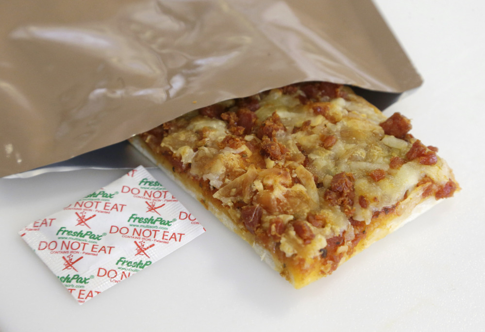 A slice of prototype pizza, in development to be used in MRE’s – meals ready to eat – sits in a packet next to a smaller packet known as an oxygen scavenger, left, at the U.S. Army Natick Soldier Research, Development and Engineering Center.
