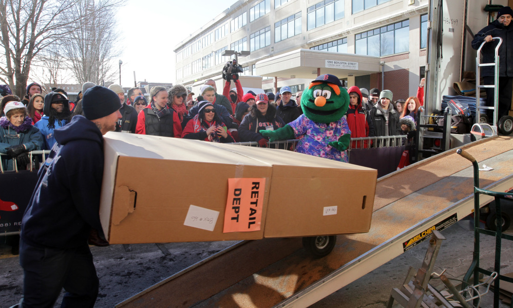 BACK AT IT: Workers load boxes into the Boston Red Sox equipment truck in front of Fenway Park in Boston last week as the team’s mascot Wally the Green Monster looks on. The truck left for spring training in Fort Myers, Fla.