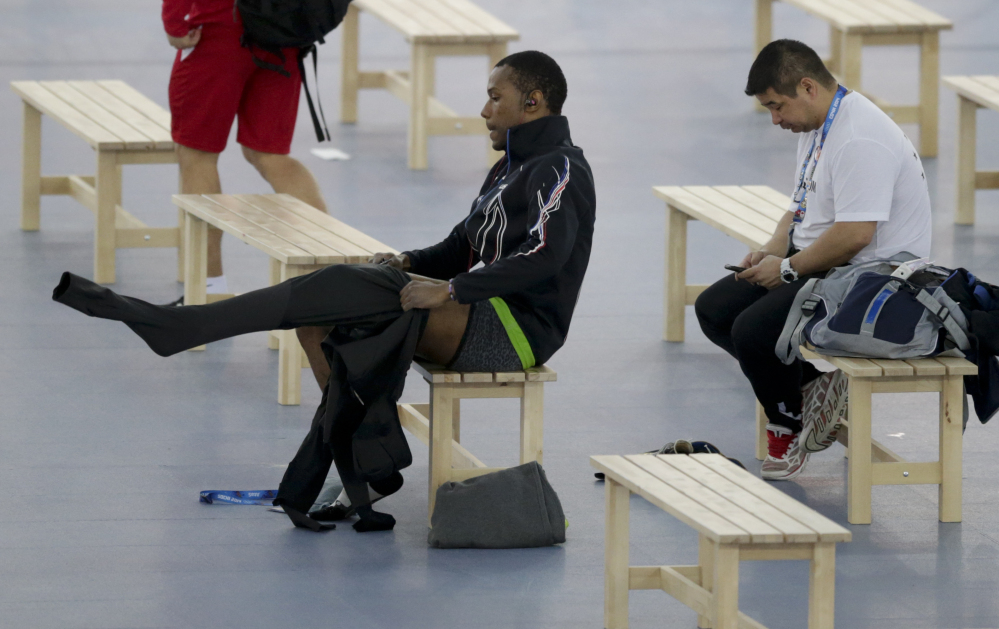 Shani Davis of the U.S., center, puts on the prototype of the official US Speedskating suit, while coach Ryan Shimabukuro checks his phone prior to a training session at the Adler Arena Skating Center at the 2014 Winter Olympics, Friday, Feb. 14, 2014, in Sochi, Russia. The team thought it had a chance to do something special, given some impressive World Cup results this season and new high-tech suits from Under Armour, which got an assist in the design from aerospace giant Lockheed Martin. Now, there’s plenty of grumbling that the suits are actually slowing the skaters down in Sochi.