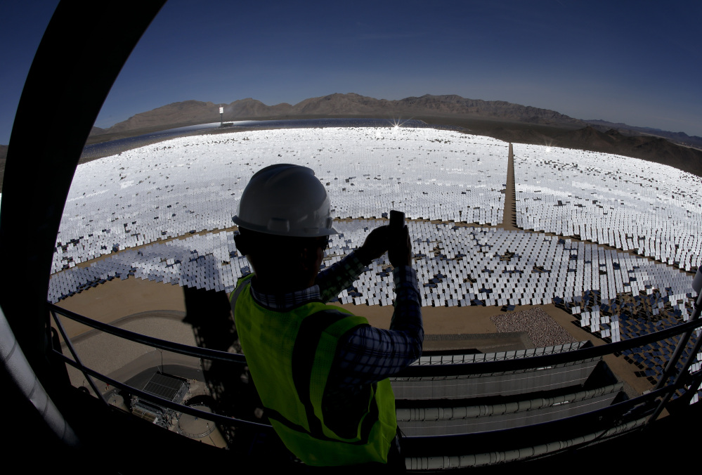 Jeff Holland takes a picture of some of the thousands of computer-controlled mirrors that reflect sunlight to boilers that sit on towers.