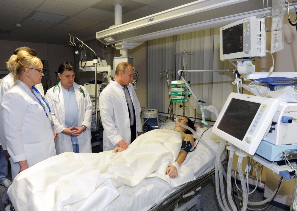 In this photo provided by RIA Novosti Kremlin, Russian President Vladimir Putin, center, speaks to skier Maria Komissarova in a hospital in Krasnaya Polyana, Russia, on Saturday. The 23-year-old Russian ski cross racer fractured her spine during a training session Saturday and underwent a 6 hour surgery.