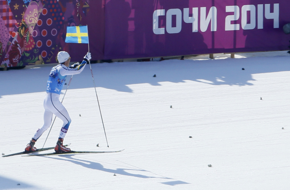Sweden’s Marcus Hellner skis with the Swedish flag as his team wins the gold during the men’s 4x10K cross-country relay at the 2014 Winter Olympics, Sunday in Krasnaya Polyana, Russia.