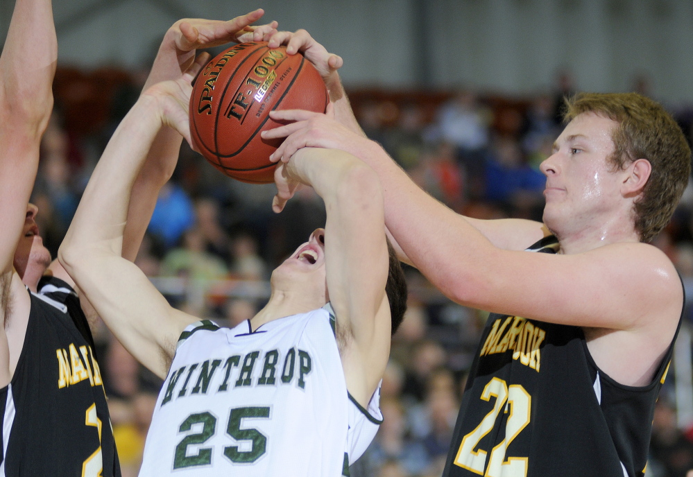 Staff photo by Andy Molloy Maranacook Community School's Cameron Brochu, left, and Brad Worster block Winthrop High School's Dakota Carter during a tournament basketball match up Monday against in Augusta.