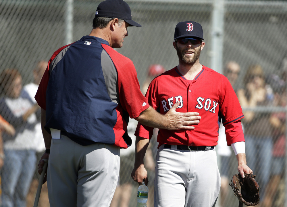 READY TO GO: Boston Red Sox manager John Farrell, left, gives Red Sox second baseman Dustin Pedroia, right, a pat on the stomach during practice Monday in Fort Myers, Fla. Pedroia says he’s ready for the season after having offseason thumb surgery.