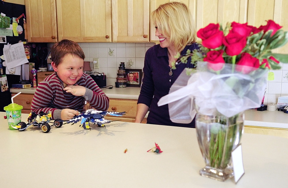 REMEMBERING: Nate Lewis, 6, laughs with his mother Lynn Lewis on Friday February 14, 2014, at their home in Monmouth. Maj. Scott Lewis, who is serving in Afghanistan, sent his son the Lego set and his wife the vase of roses for Valentine’s Day.