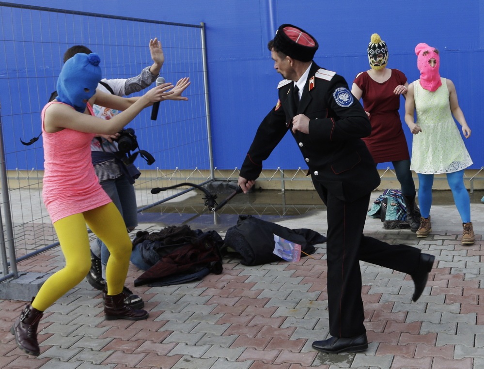 A Cossack militiaman attacks Nadezhda Tolokonnikova and a photographer as she and fellow members of the punk group Pussy Riot stage a protest performance Wednesday. The group had gathered in a downtown Sochi restaurant, about 21 miles from where the Winter Olympics are being held. They ran out of the restaurant wearing brightly colored clothes and ski masks and were set upon by about a dozen Cossacks, who are used by police authorities in Russia to patrol the streets.