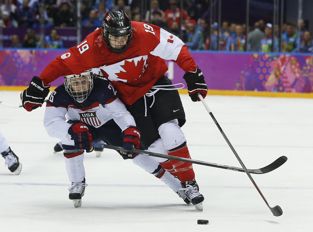 Kendall Coyne of the United States (26) reaches under Brianne Jenner of Canada (19) during the third period of the women’s gold medal ice hockey game.