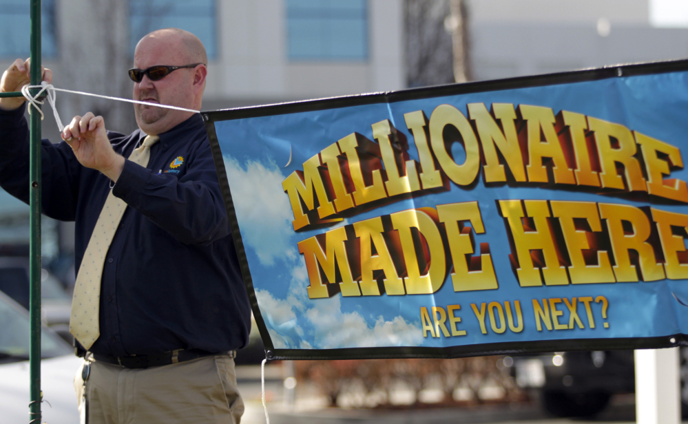 California Lottery official John Reading hangs a “Millionaire Made Here” sign at the Dixon Landing Chevron that sold a winning $425 million Powerball ticket in Milpitas, Calif. The owners of the station received a $1 million bonus for selling the ticket.