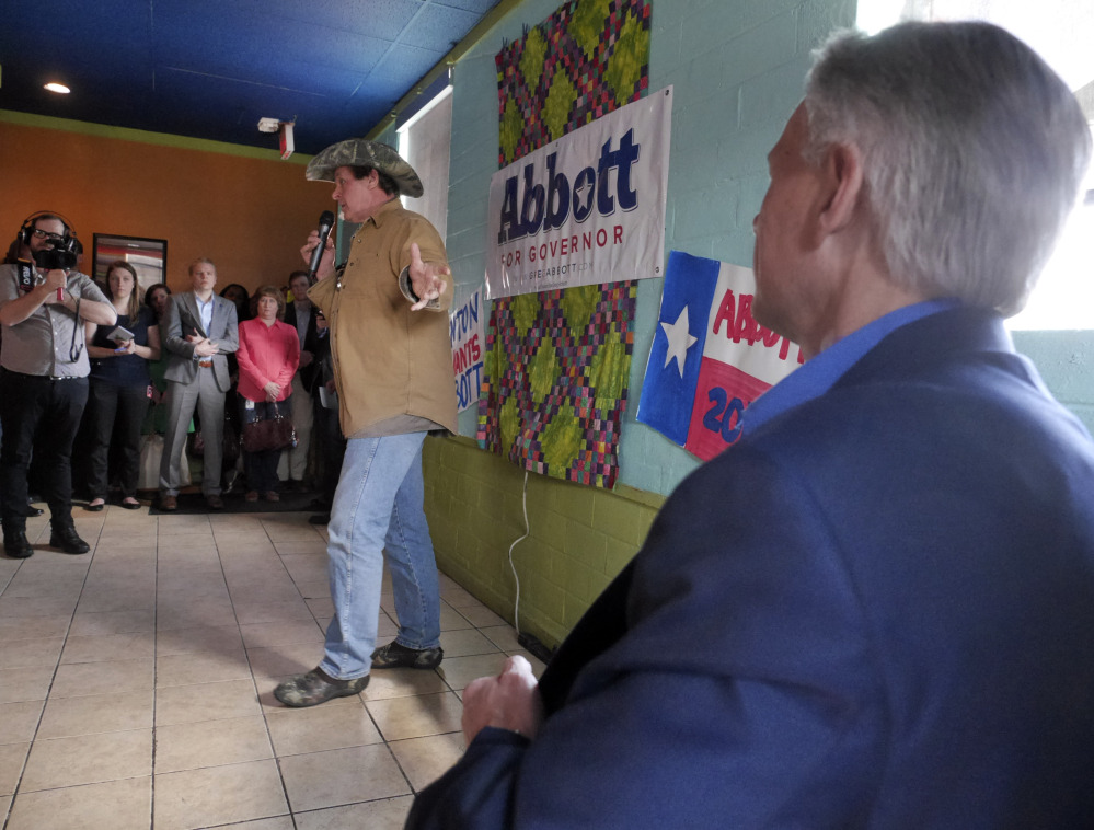 Rocker Ted Nugent, left, introduces Texas gubernatorial candidate Greg Abbott, Tuesday during a stop in Denton, Texas, to promote early voting. Wendy Davis is the Democratic opponent.