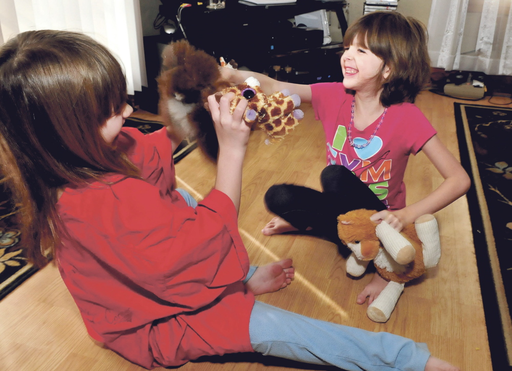 Normal life: Kaitlyn Parker, right, and her sister Briana play with toys Wednesday at their home in Augusta. Kaitlyn is dealing with a medical condition known as Marfan syndrome, a genetic disorder that can affect ligaments and the heart.