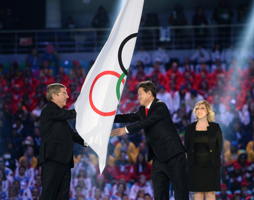 International Olympic Committee President Thomas Bach, left, hands the Olympic flag to Lee Seok-rai, mayor of Pyeongchang, during the closing ceremony of the 2014 Winter Olympics on Sunday in Sochi, Russia.