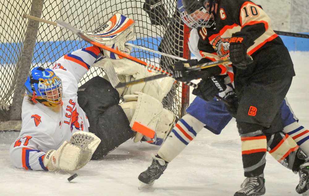 Staff photo by Michael G. Seamans Skowhegan/Lawrence goalie Sam Edmondson, 27, makes a save in as Brunswick High School’s Cam Heatley, 10, looks for the rebound in the second period at Sukee Arena in Winslow on tuesday.
