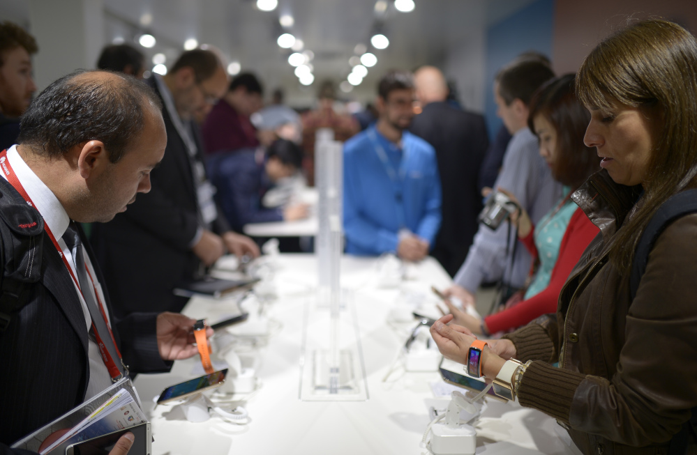 Visitors check the new devices of Samsung at the Mobile World Congress, the world’s largest mobile phone trade show in Barcelona, Spain, Tuesday.