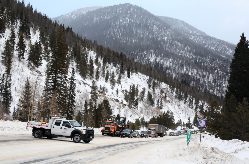 In this Feb. 21, 2014 photo, Colorado Department of Transportation employees stop traffic as they use an explosives launcher to try to trigger a controlled avalanche, near Empire, Colo. Lots of new snow and strong winds in the past month have fueled dangerous conditions from the Cascades to the Rockies, prompting forecasters to issue warnings of considerable or high avalanche dangers for many areas outside of established ski areas. (AP Photo/Brennan Linsley)