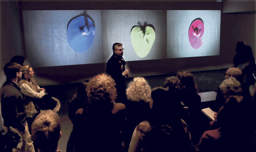 DAZZLING: Ahmed Abdalla, artist and co-curator of the exhibit “Histories of Now: Six Artists of Cairo,” speaks in front of the video art installation titled “Merge and Emerge” of Egyptian dancers twirling in colorful garments at the Colby College Museum of Art in Waterville on Thursday.