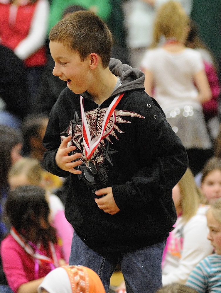 ACHIEVEMENT: Fifth-grader T.J. Jackson jumps up to get another one when his name is called for a third time during a medal ceremony for academic test scores on Thursday at Farrington School in Augusta.