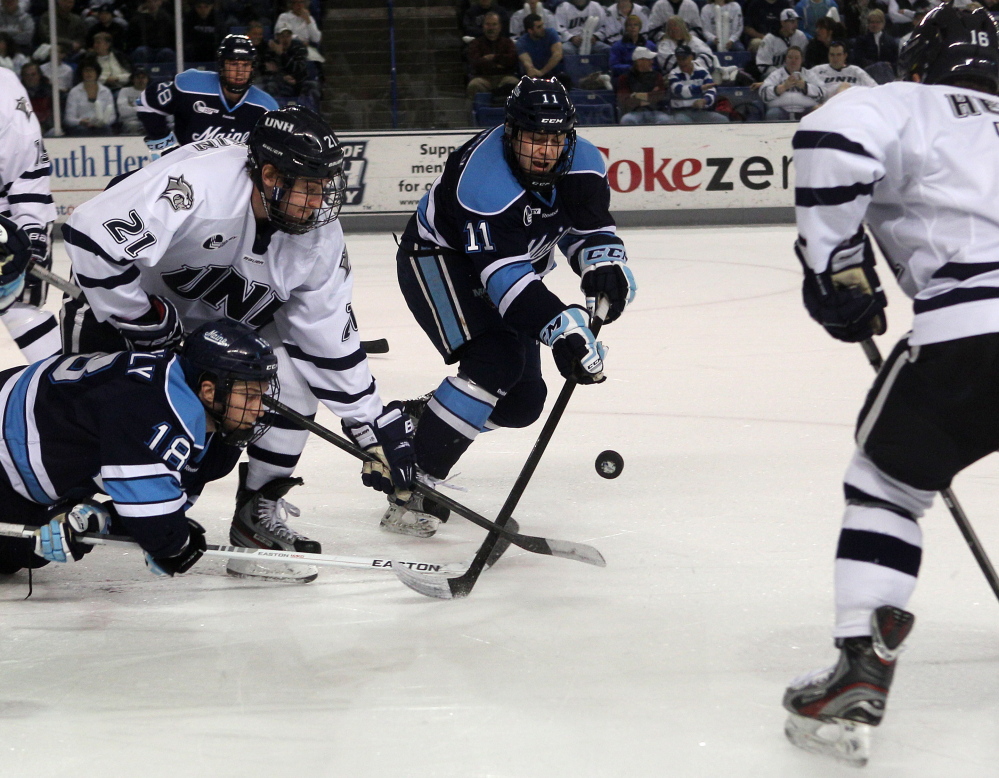 ONE LAST TIME: New Hampshire’s Nick Sorkin (21) works to control a face off against Maine’s Jon Swavely (18) and Steven Swavely (11) during the first period last season at the Whittemore Center in Durham, N.H. The brothers are hoping to extend their time together playing for the Black Bears.