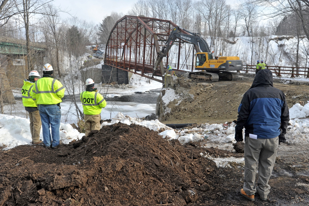 BIG DIG: An excavator digs the embankment away from the New Sharon bridge next to U.S. Route 2 during demolition on Thursday.