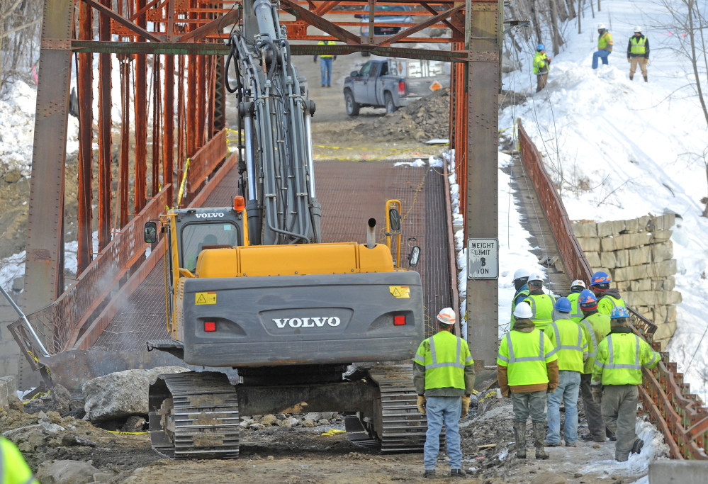 BRIDGE WORK: Crews stand by as an excavator jackhammers the New Sharon bridge on Thursday. The initial controlled explosions failed to bring down the historic bridge, but it was brought down several hours later by excavators.
