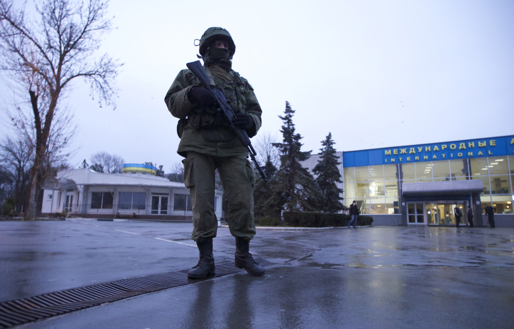 An unidentified man patrols a square in front of the airport in Simferopol, Ukraine, on Friday. Dozens of armed men in military uniforms without markings occupied the airport in the capital of the strategic Crimea region.
