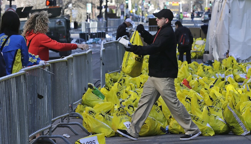 In this April 16, 2013 file photo, a worker returns a bag containing a runner's personal effects near the finish line of the Boston Marathon, after bombs placed in backpacks killed three people and inured more than 260 in Boston. This year's Boston Marathon will have a "no bags" policy as part of stepped-up security following last year's deadly bombing.