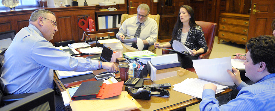 Gov. Paul LePage reaches for a pen while working on his third State of the State address Monday with his Chief of Staff John McGough, right, Press Secretary Adrienne Bennett and Director of Communications Peter Steele in the governor's office in Augusta.