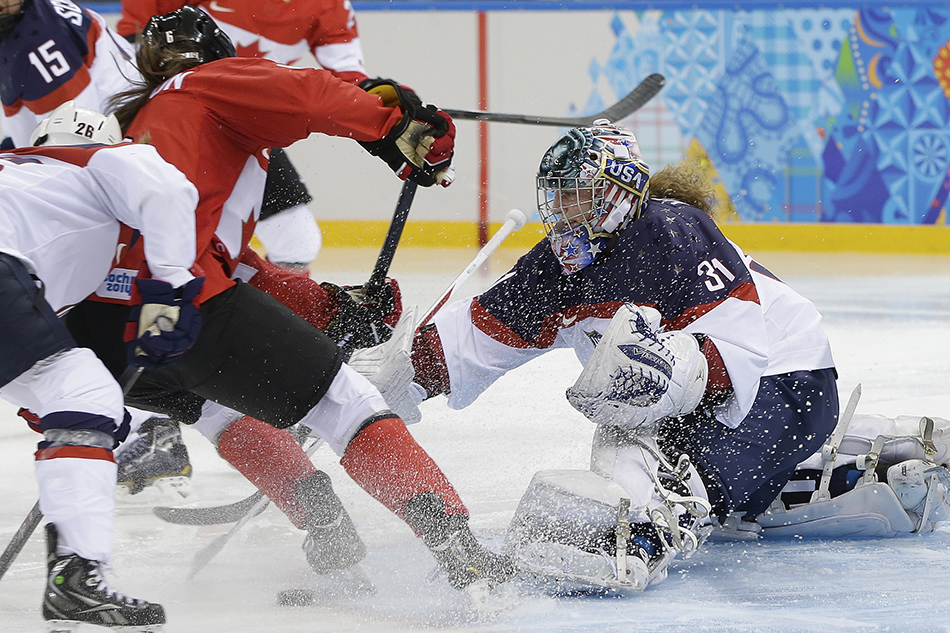 Rebecca Johnston of Canada takes a shot at the goal as USA Goalkeeper Jessie Vetter reaches for the puck during the second period of the 2014 Winter Olympics women's ice hockey game at Shayba Arena, Wednesday, Feb. 12, 2014, in Sochi, Russia.