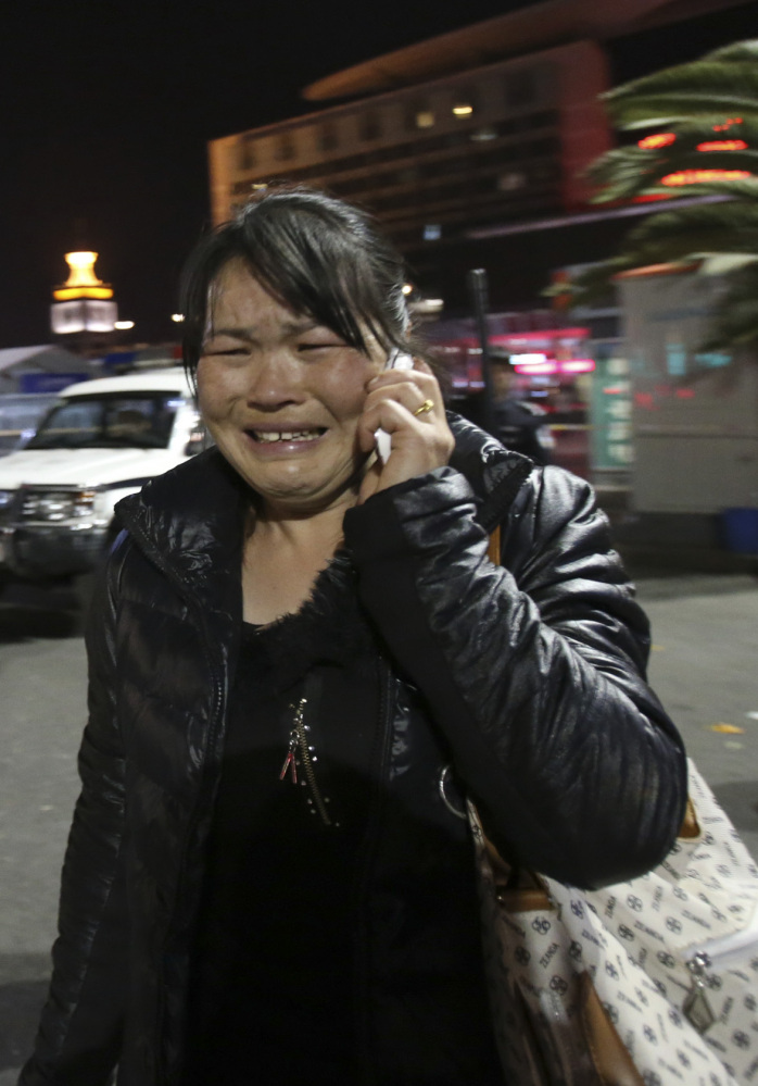 A woman makes a call from the crime scene outside a railway station in Kunming, China, on Saturday.