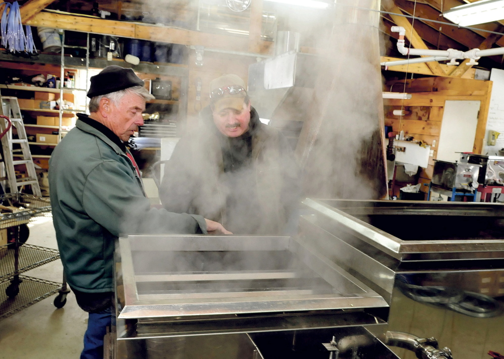 BOILING READY: Bob Bacon, left, of the Bacon Farm in Sidney, speaks with Jim Wright of Apple Ridge maple syrup operation in Cornville as steam rises from a sap evaporator in Sidney on Monday. Bacon said it was the second time he boiled syrup this season and expects his operation to increase this weekend as temperatures rise.
