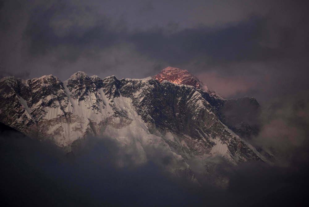 The last light of the day sets on Mount Everest as it rises behind Mount Nuptse in Nepal. The Everest climbing season began Saturday with new rules that require climbers to bring down at least 17.6 pounds of their personal garbage.