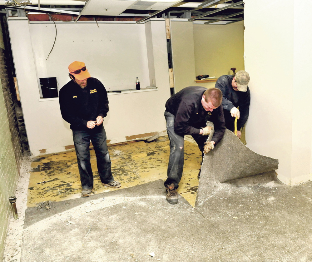 NEW FLOORS: Waterville Public Works employees Joey Meunier, left, Bobby Bellows and Mike Folsom rip up carpet while renovating one of the rooms of the former police department in the basement of City Hall on Thursday.