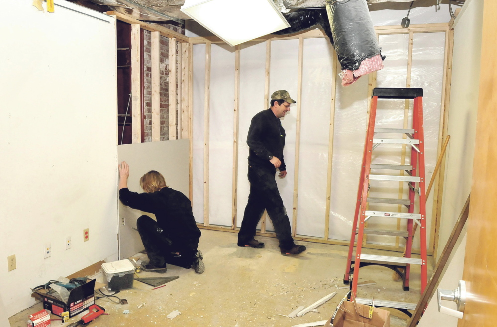 WORK IN PROGRESS: Waterville Public Works employees Jacob Chambers, left, and Dan Main renovate a former city detective’s office in the City Hall basement on Thursday. The former police station space will be used for storage.