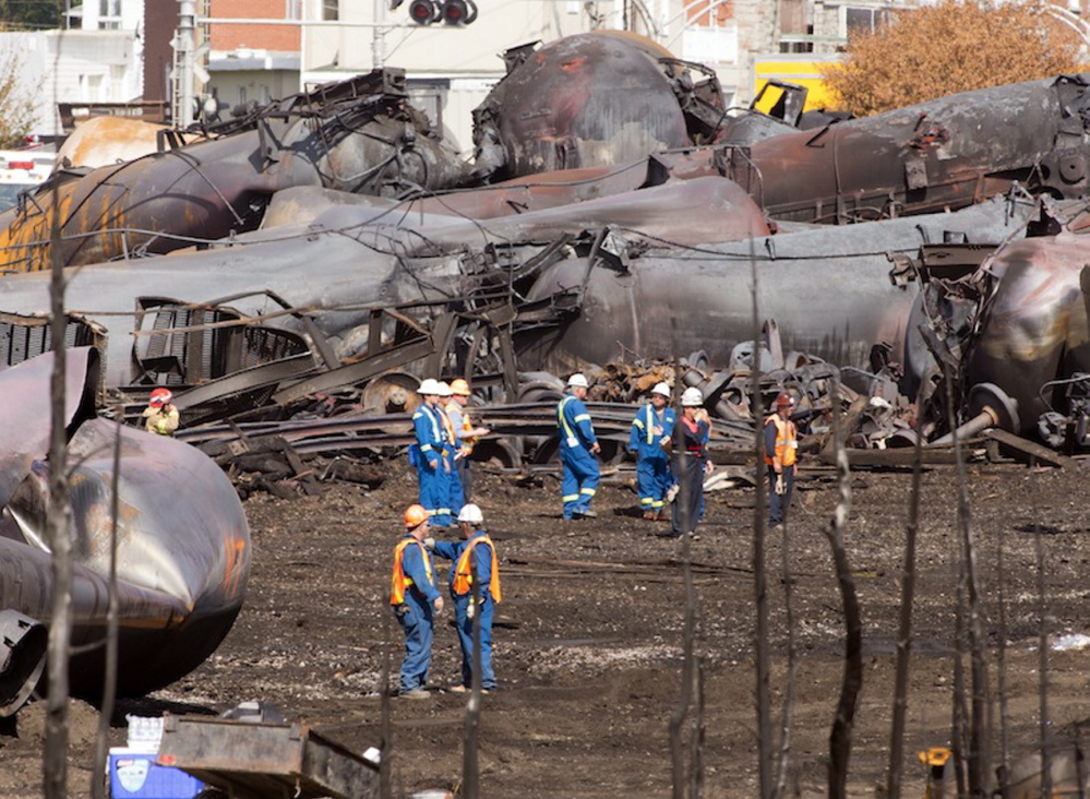 Workers stand before mangled tanker cars in July at the crash site of the train derailment and fire in Lac-Megantic, Quebec. The U.S. Department of Transportation has said the industry’s unsafe handling procedures pose a hazard.