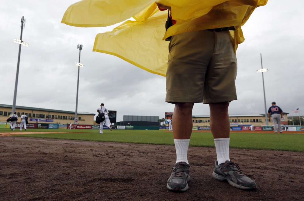 NO FUN: An usher wears a rain poncho as wind kicks up, storm clouds move in and Miami Marlins’ Rafael Furcal (15) leaves the field after playing in a spring training game Thursday against the Boston Red Sox, Thursday in Jupiter, Fla. The game was called with a 0-0 score after eight innings.