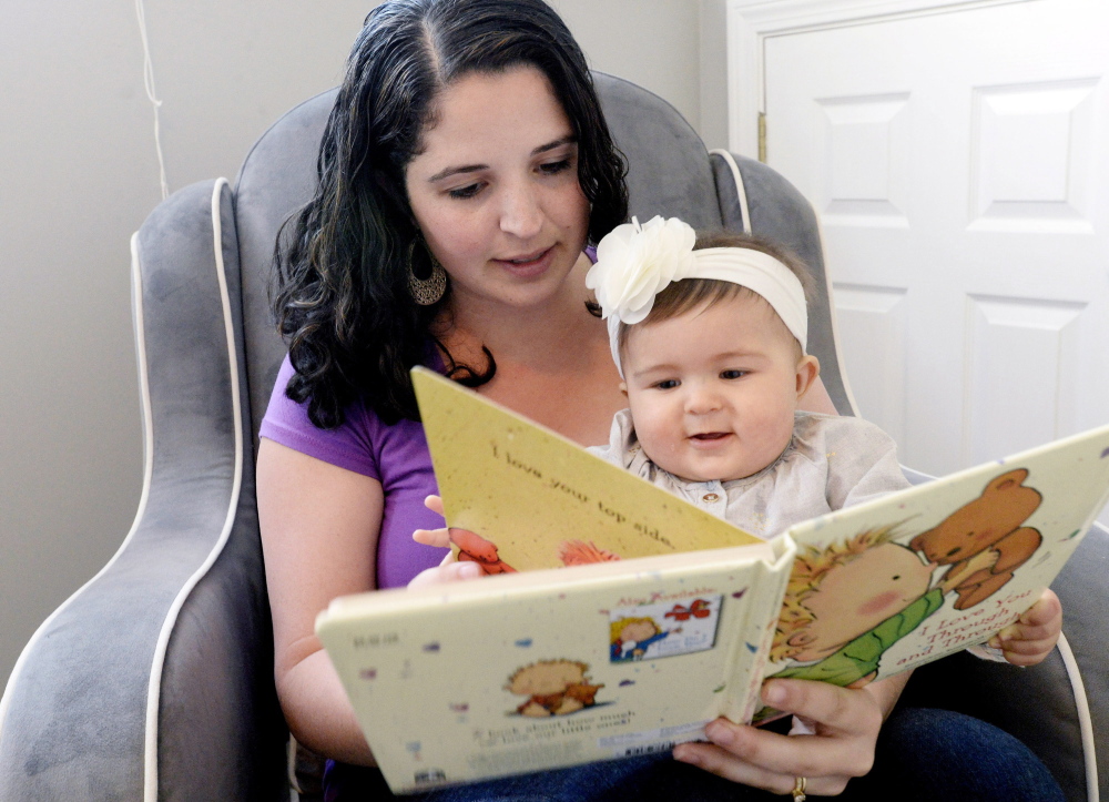 Hannah Richards of Windham reads to her daughter, Mia, at their home Thursday. “It’s a big help,” she said of the $500 grant.