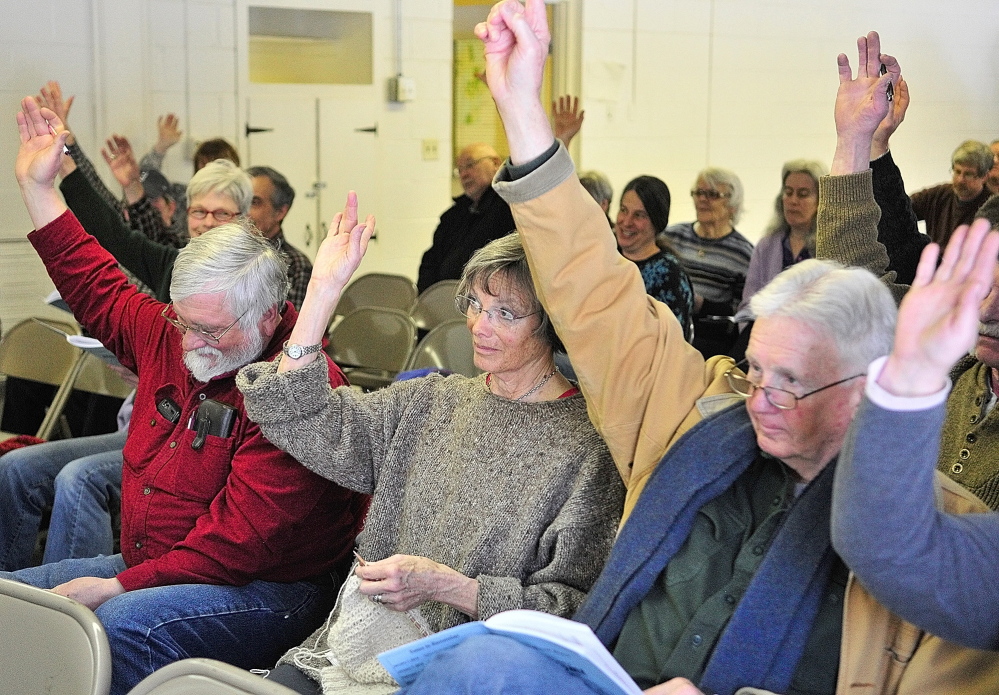 DECISION TIME: Peter Kallin, left, Sue Greenan and Dick Greenan vote from the front row Saturday during the Rome Town Meeting .