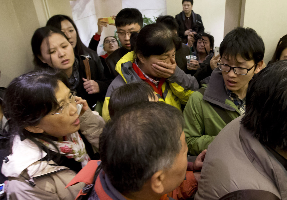A woman, surrounded by members of the media, arrives at a hotel prepared for relatives and friends of passengers aboard a missing airplane, in Beijing on Saturday.