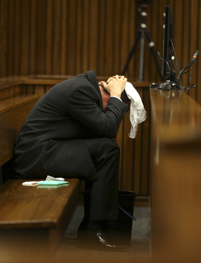 Oscar Pistorius covers his head on Monday after he had reached for a bucket at his feet while listening to cross questioning about the shooting death of his girlfriend, Reeva Steenkamp. Pistorius is charged with the shooting death of Steenkamp on Valentine's Day in 2013.
