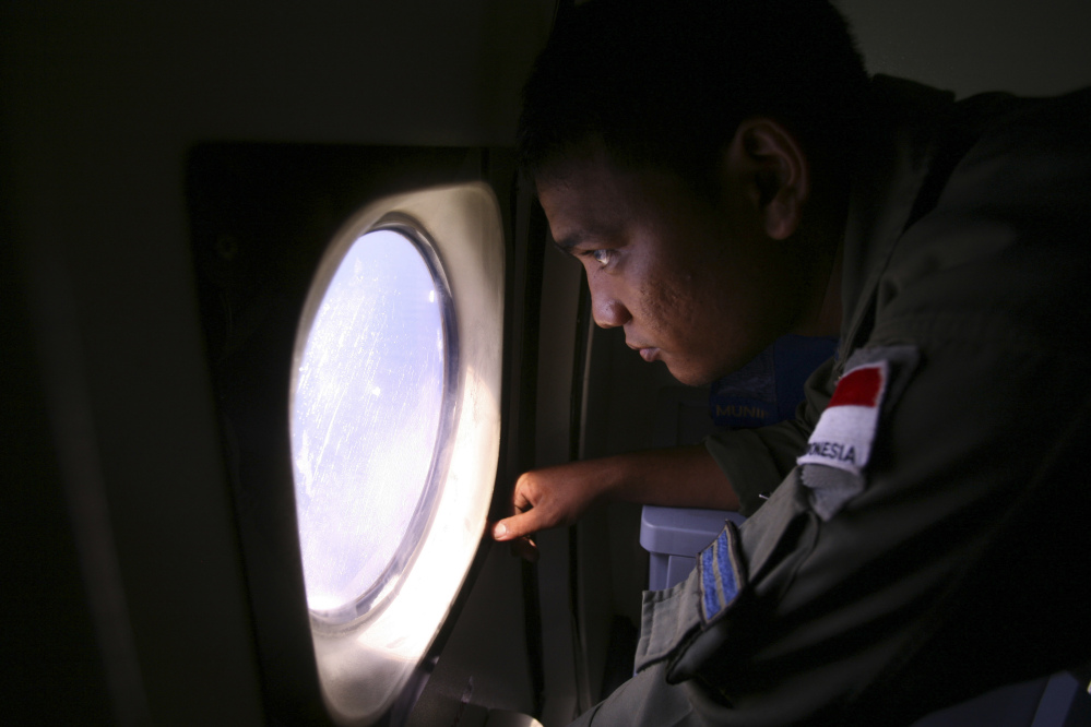 An Indonesian Navy crew member scans the water bordering Indonesia, Malaysia and Thailand during a search operation for the missing Malaysian Airlines Boeing 777 near the Malacca straits on Monday.