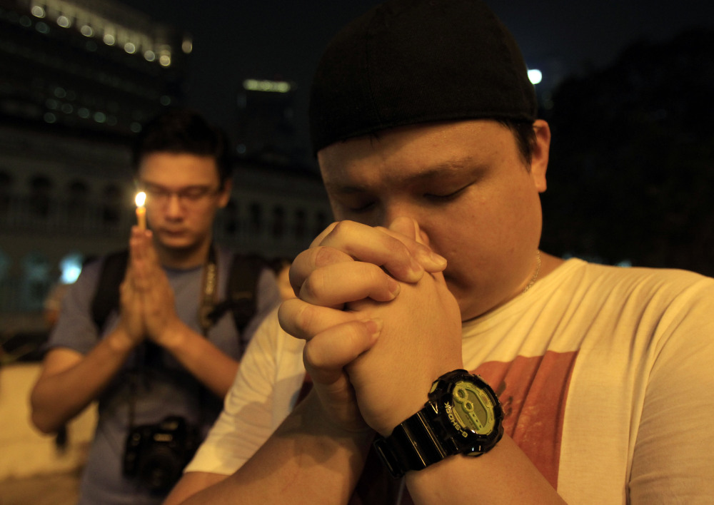 Men offer prayers during a candlelight vigil for passengers aboard a missing Malaysia Airlines plane in Kuala Lumpur, Malaysia, on Monday.