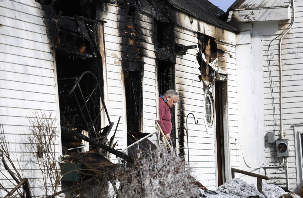 Fire investigator Dan Young leaves a Limington home Monday after taking photos in the aftermath of a fire that killed a woman earlier that morning. The fire was reported by a passer-by at 5:30 a.m., and firefighters arrived minutes later to find the house engulfed in flames.